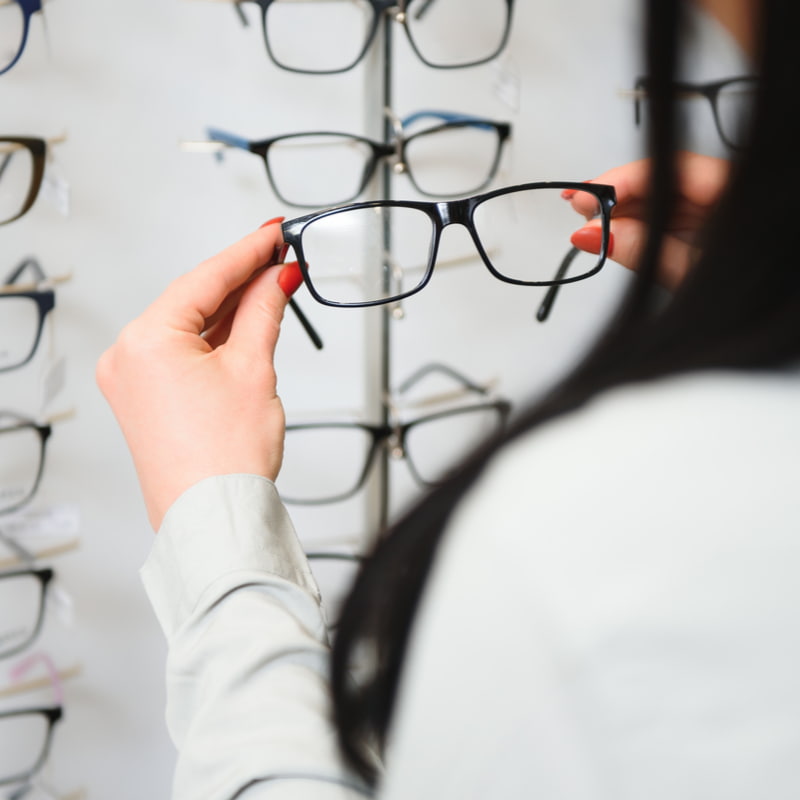 Woman selecting some reading glasses off of a wall display